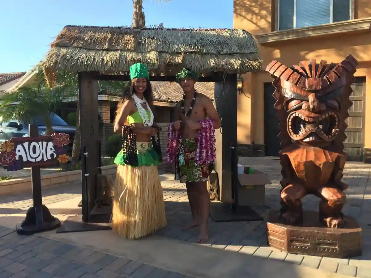 Lei Greeters Beside a Grass Shack, Aloha Sign and Carved Tiki